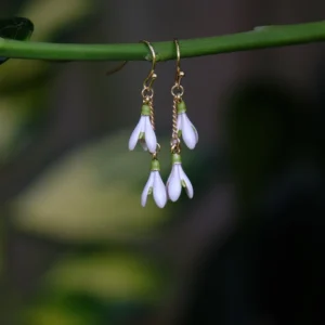 Gold plated snowdrop flower drop hook earrings with white and green enamel floral design, elegant botanical jewellery with hypoallergenic hooks, lightweight drop earrings inspired by nature.
