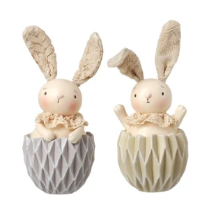 Baby bunny ornament inside a cracked egg shell with rosy cheeks, pink nose, and spring-mounted wobble ears, available in light grey or beige for Easter and spring decor.