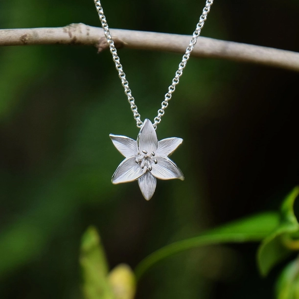 Silver plated white lily pendant necklace with hand enamel white flower design, elegant botanical jewellery on an adjustable chain, ideal for pairing with the matching White Lily Stud Earrings.