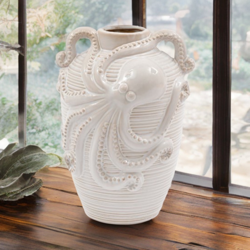 White ceramic octopus vase with two curved handles, glossy finish, ridged texture, and sculpted tentacles wrapping around the body, styled as nautical coastal home décor.