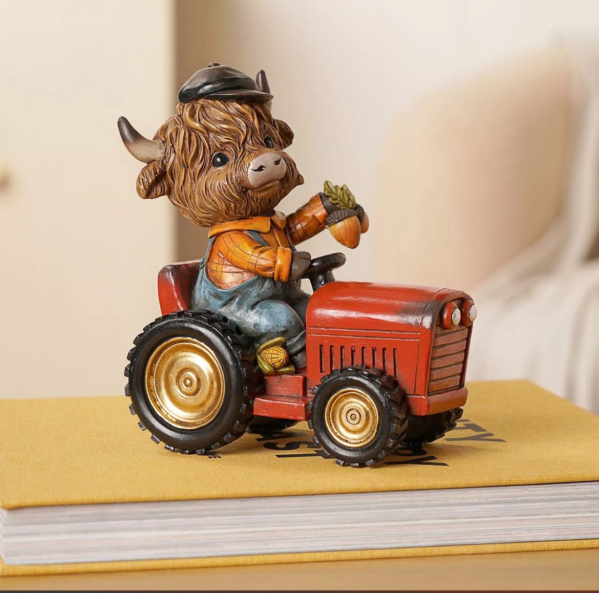 Highland cow driving a red tractor resin ornament with rustic farmyard details, perfect for autumn, harvest and countryside home decor.