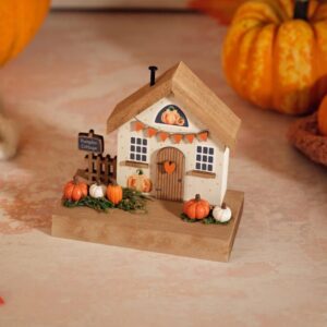 Harvest Home wooden Pumpkin Cottage decoration with tan roof, white cottage, painted windows and door, miniature orange and white pumpkins, brown fence, and Pumpkin Cottage sign on a wooden base.