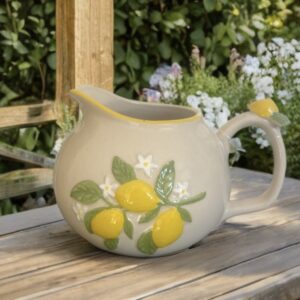 Mini ceramic lemon jug with raised yellow lemons, green leaves and white blossom design on a cream glazed finish.