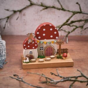 Toadstool Tales wooden Mushroom Place decoration featuring two red and white spotted mushroom houses, a wooden mouse, miniature mushrooms, faux grass, painted windows and doors, and a Mushroom Place sign.