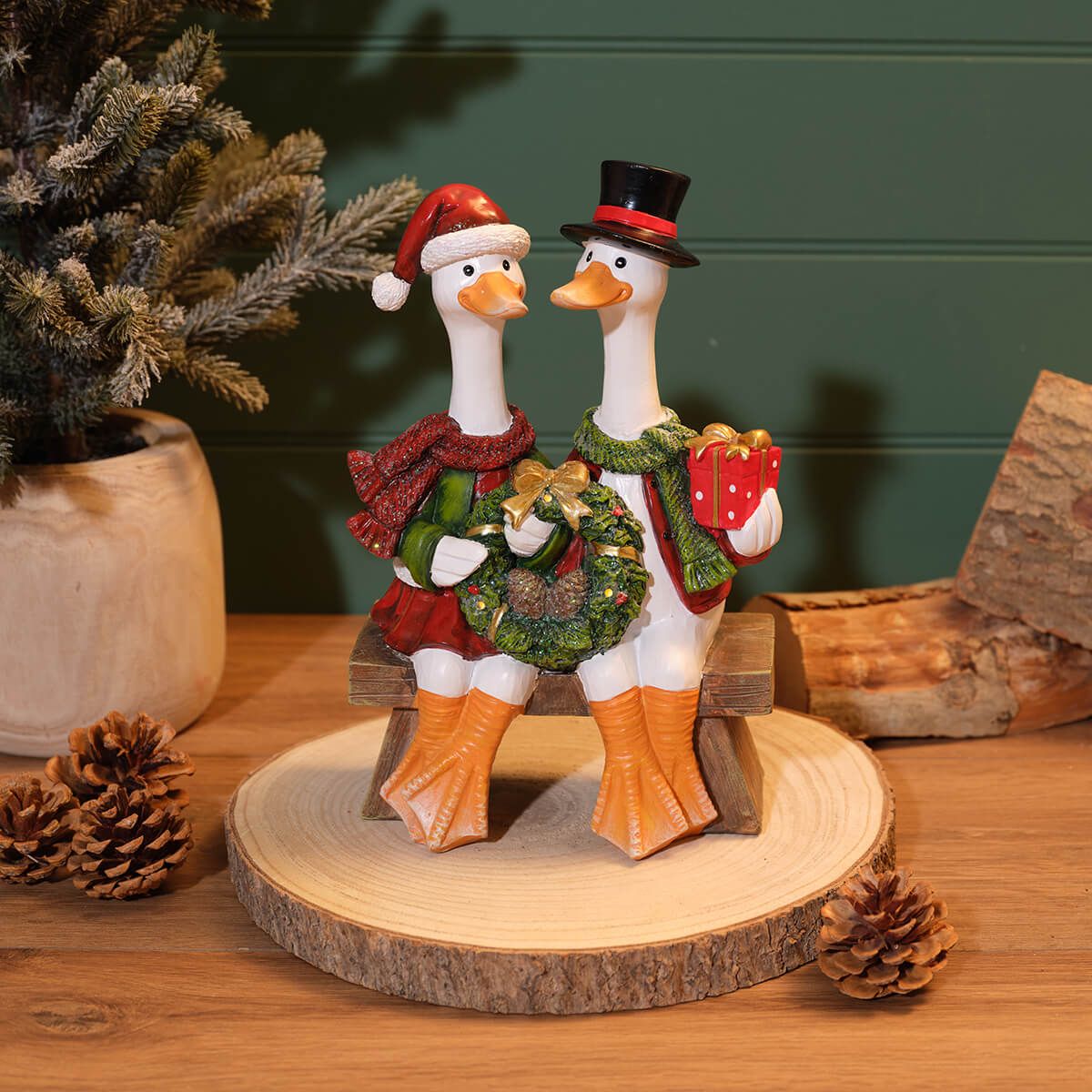 Mr and Mrs Duck resin Christmas ornament on bench with festive clothing, wreath, gift box and LED lights